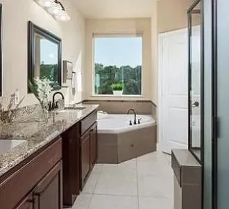 a bathroom with a granite countertop tub sink and mirror