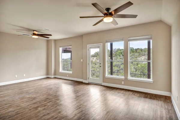 a view of an empty room with a window and wooden floor