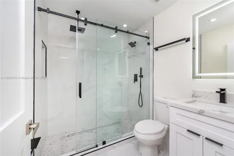 a bathroom with a granite countertop toilet sink and shower
