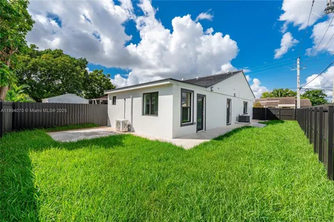 a view of a white house next to a yard with big trees