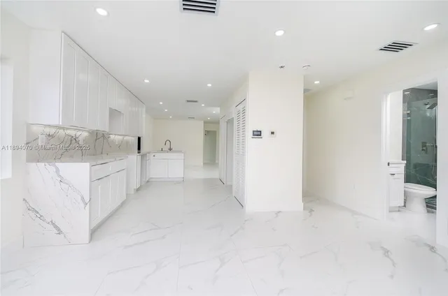 a view of kitchen with white cabinets and sink