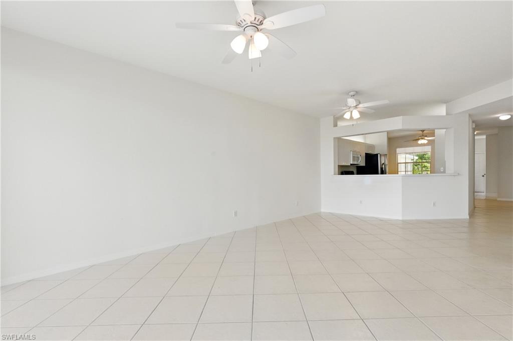 3460 West Crown Pointe Boulevard, Unit 101 Naples, FL 34112 - Photo 14 of 43 an empty room with fan and kitchen view