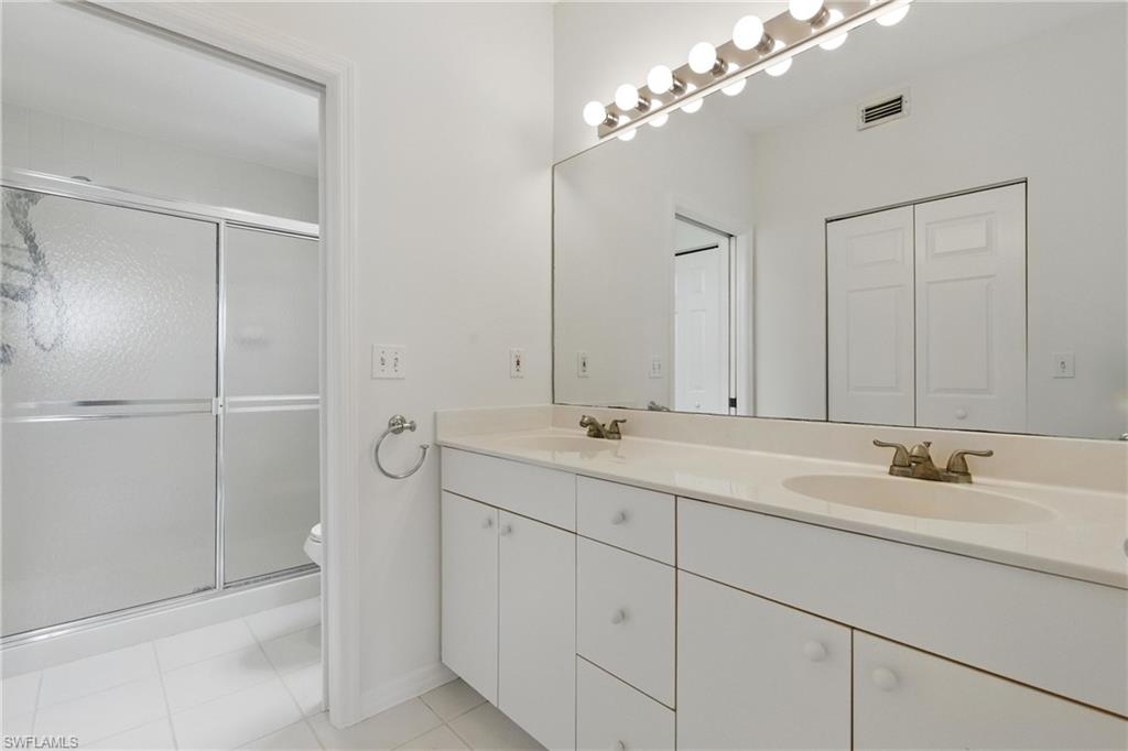 3460 West Crown Pointe Boulevard, Unit 101 Naples, FL 34112 - Photo 21 of 43 a bathroom with a double vanity sink a large mirror and shower