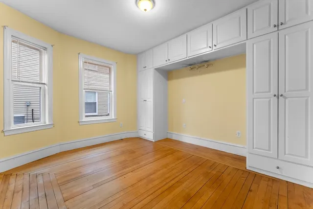 an empty room with wooden floor cabinet and windows