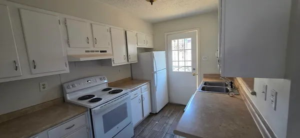 a kitchen with granite countertop a sink a stove and refrigerator