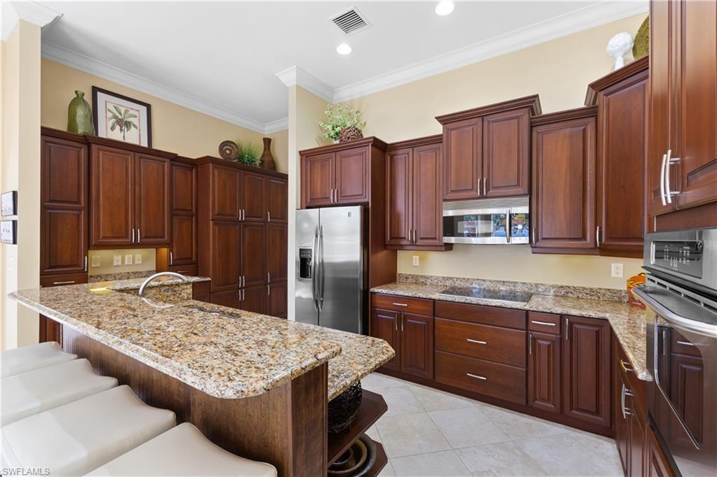 20398 Foxworth Circle Estero, FL 33928 - Photo 30 of 50 a kitchen with kitchen island granite countertop wooden cabinets a refrigerator and a sink