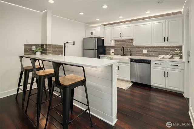 a kitchen with stainless steel appliances granite countertop a table chairs sink refrigerator and microwave