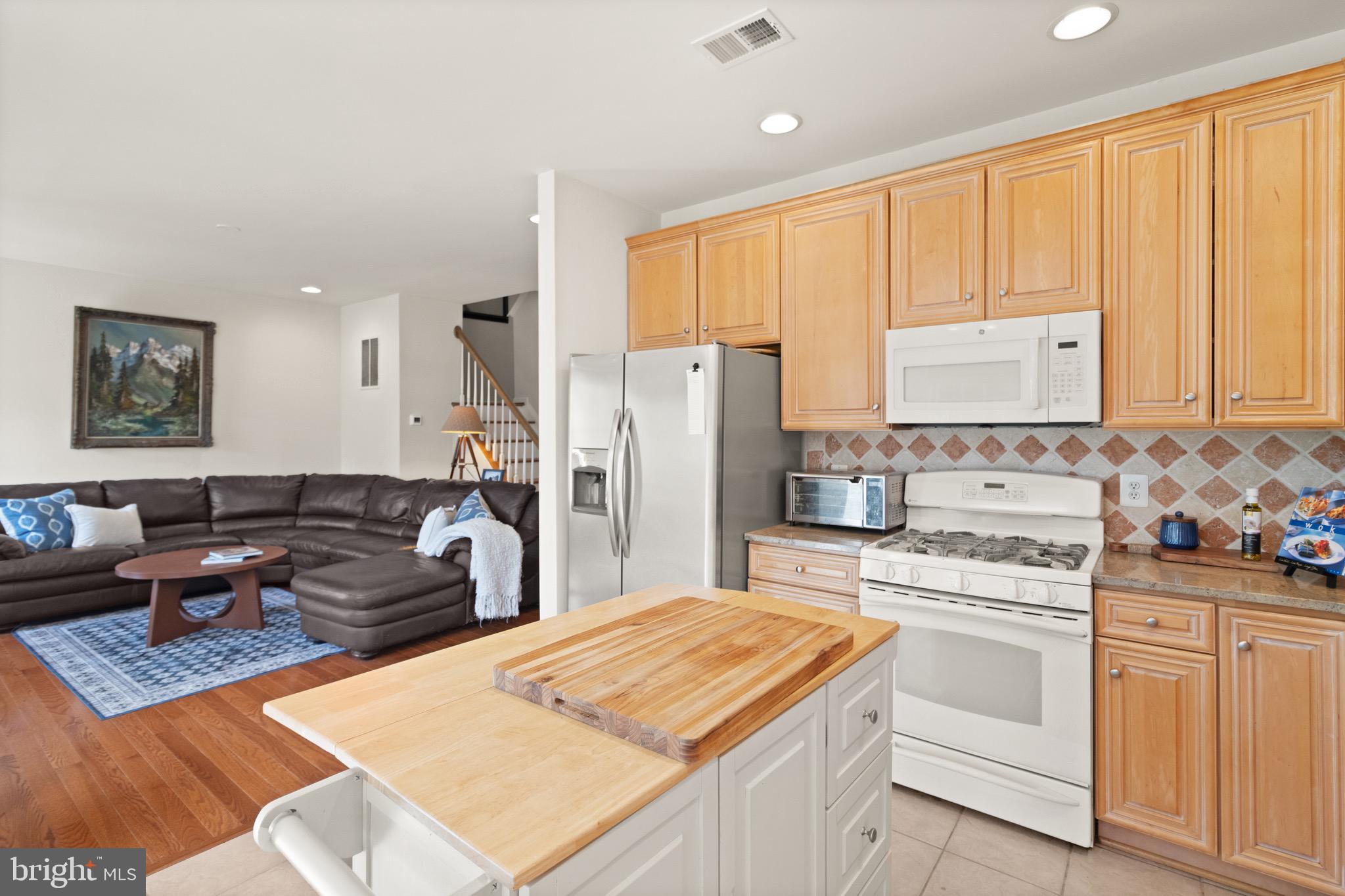 5652 Wheelwright Way Haymarket, VA 20169 - Photo 5 of 32 a kitchen with stainless steel appliances kitchen island granite countertop a refrigerator stove oven sink and white cabinets with wooden floor
