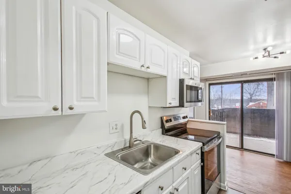 a kitchen with stainless steel appliances granite countertop a sink and a white cabinets
