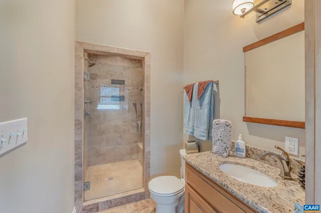 a bathroom with a granite countertop sink a toilet and shower