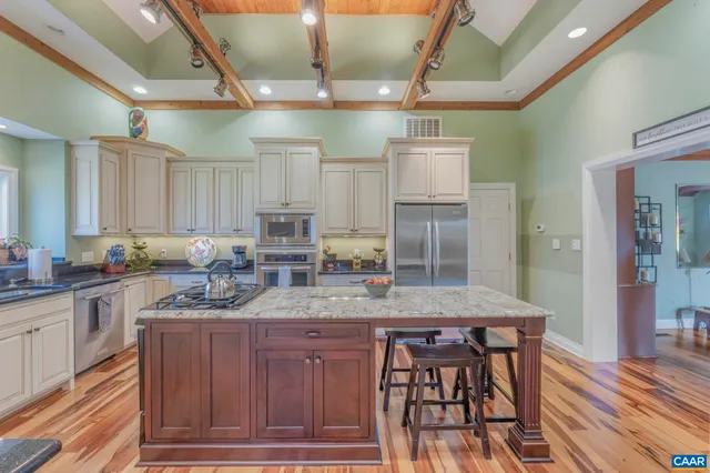 a kitchen with kitchen island granite countertop a table chairs sink and cabinets