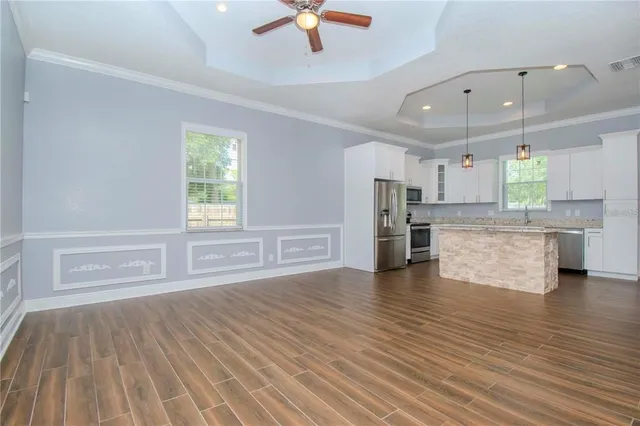an empty room with wooden floor kitchen view and a kitchen