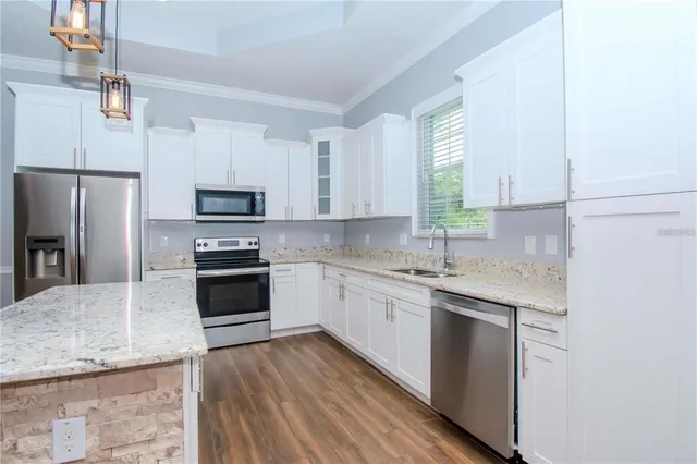 a kitchen with stainless steel appliances granite countertop a sink stove microwave and refrigerator