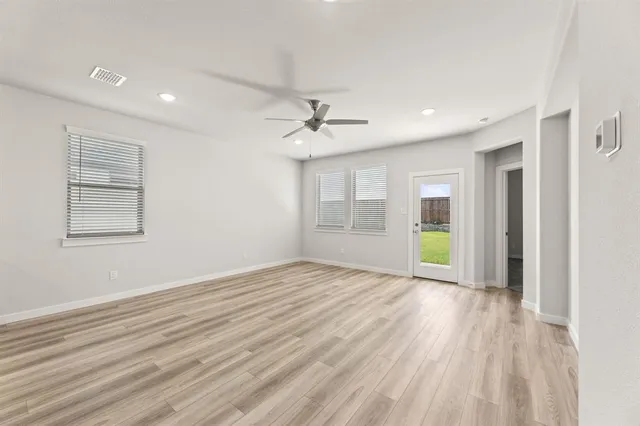 a view of an empty room with a window and wooden floor