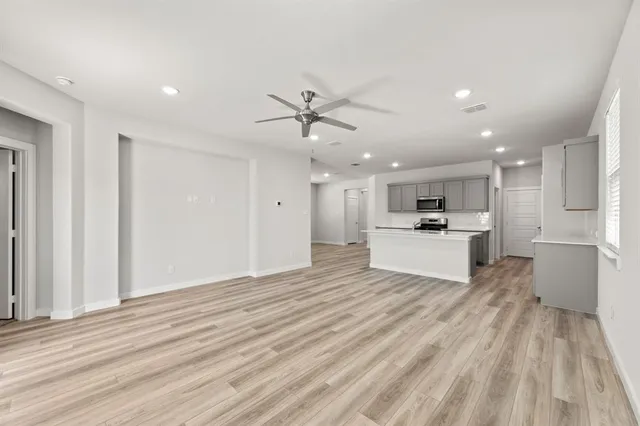 a view of kitchen with microwave oven stove and white cabinets with wooden floor