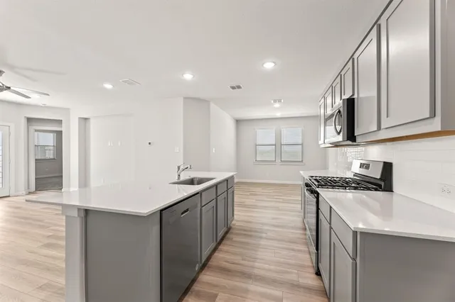 a kitchen with stainless steel appliances granite countertop a sink stove and cabinets