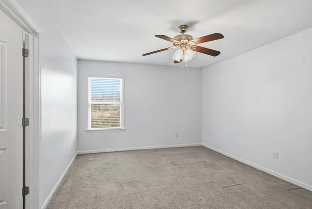 a view of empty room with window and ceiling fan