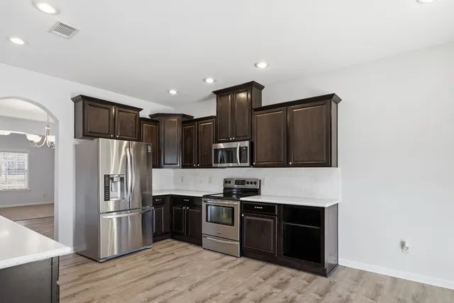 a kitchen with stainless steel appliances granite countertop a refrigerator and a stove top oven