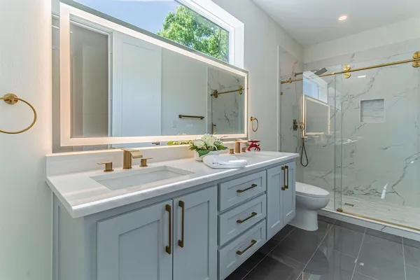 a bathroom with a double vanity sink toilet mirror and shower