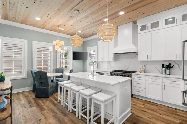 a kitchen with stainless steel appliances granite countertop a stove a sink dishwasher and white cabinets with wooden floor