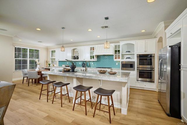 a kitchen with stainless steel appliances a stove a sink a oven a table and chairs