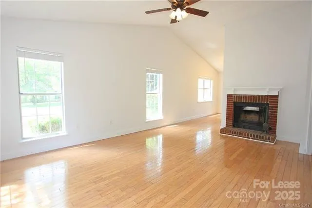 an empty room with windows and fireplace