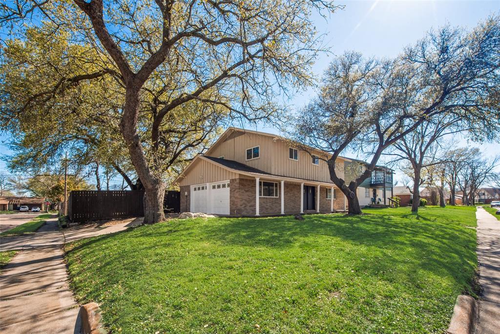 View of front facade featuring fence, driveway, a front lawn, brick siding, and a garage