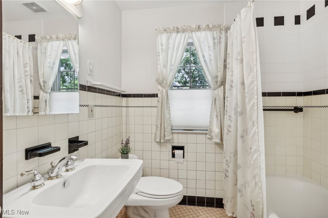 681 Merriman Road Akron, OH 44303 - Photo 25 of 43 The second floor bathroom servicing the additional bedrooms features tile floors, tile walls, a built-in vanity, and toilet.