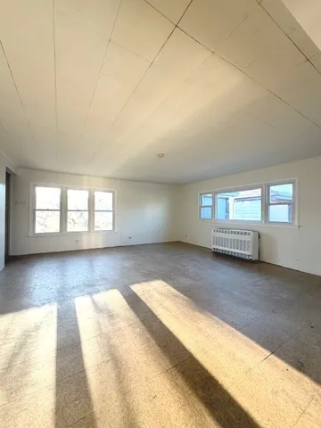 a view of an empty room and window and wooden floor