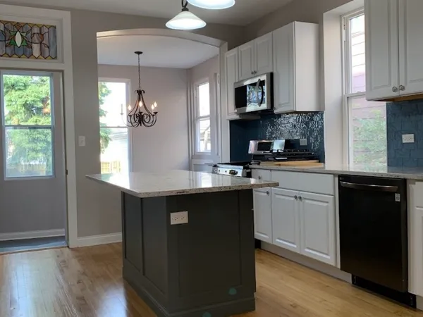 a kitchen with stainless steel appliances granite countertop a sink and wooden floor