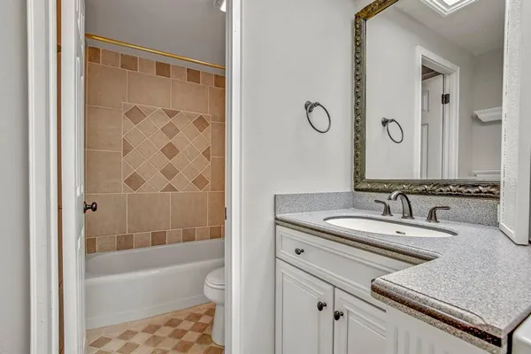 a bathroom with a granite countertop sink mirror toilet and bathtub
