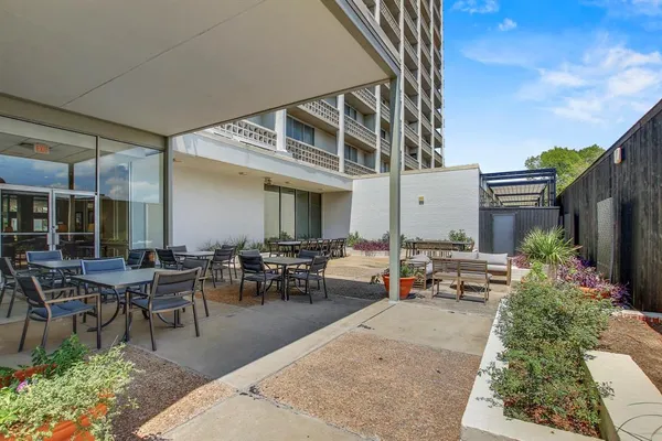 a view of a patio with table and chairs potted plants and floor to ceiling window