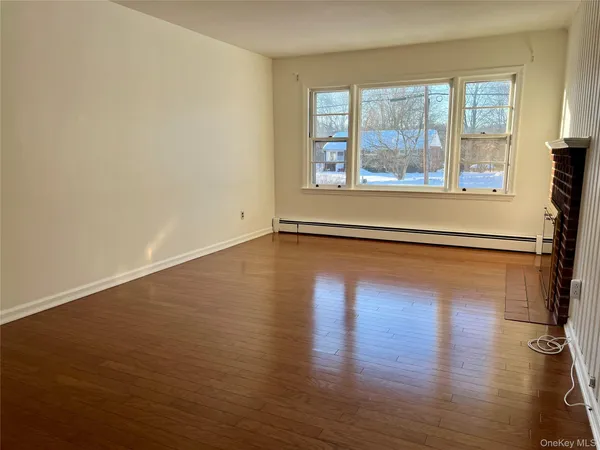 an empty room with wooden floor chandelier and windows