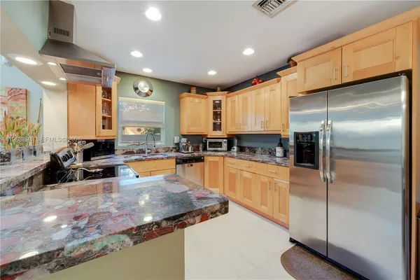 a kitchen with stainless steel appliances granite countertop a sink refrigerator and cabinets