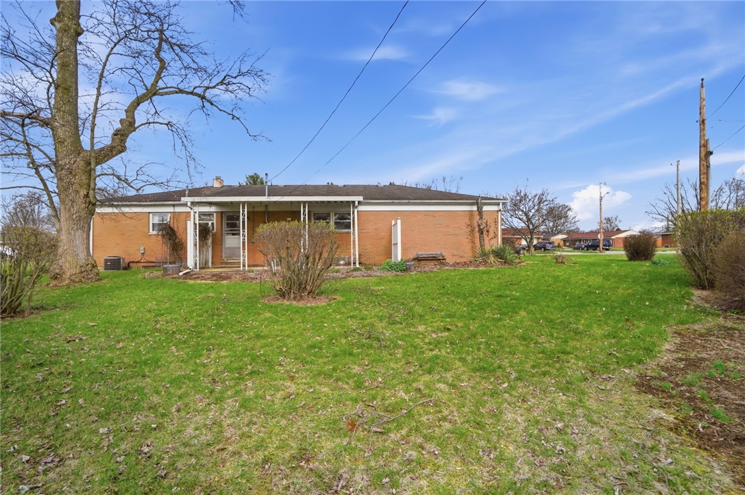 1087 Fairfield Road Troy, OH 45373 - Photo 38 of 39 This ranch-style residence features a spacious yard and classic brick construction under a bright blue sky.
