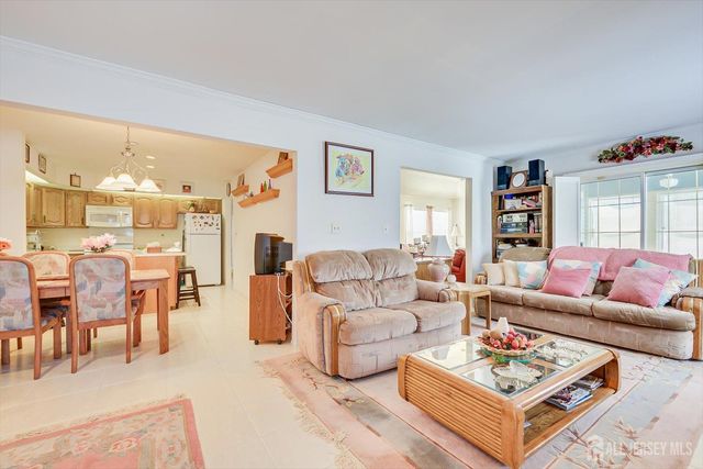 a kitchen with stainless steel appliances kitchen island granite countertop a dining table chairs and a refrigerator