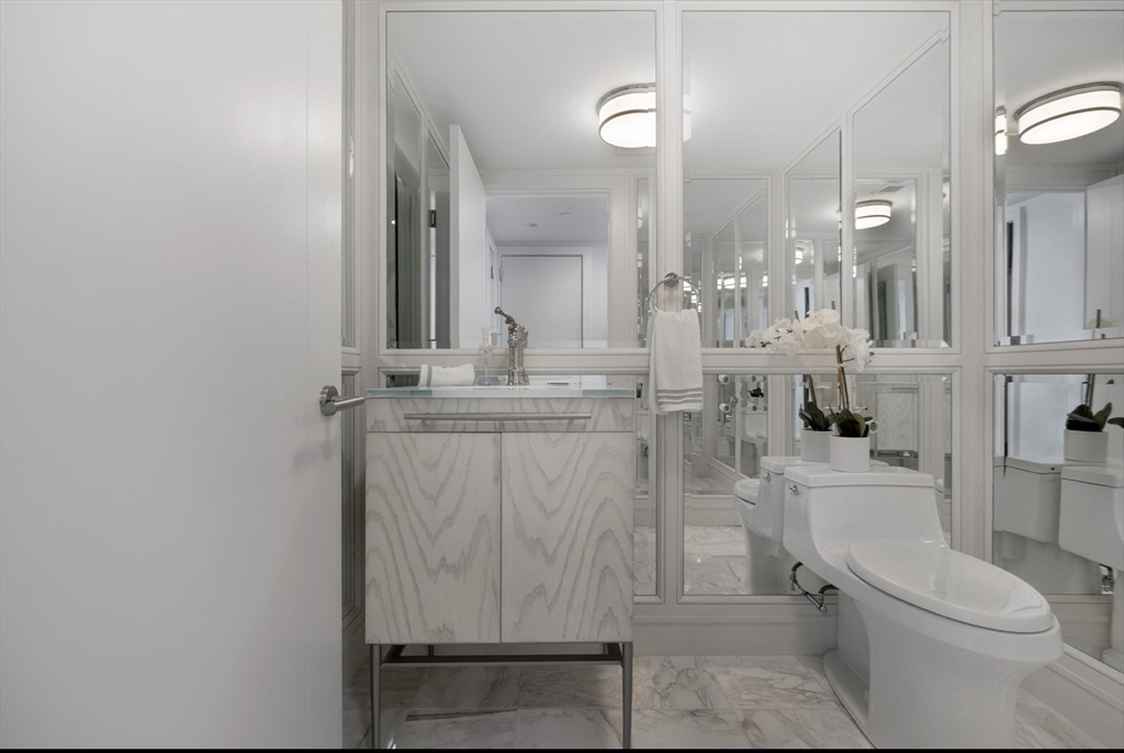 4 Battery Wharf, Unit PH 46 Boston, MA 02109 - Photo 32 of 39 a bathroom with a granite countertop sink a toilet a mirror and shower