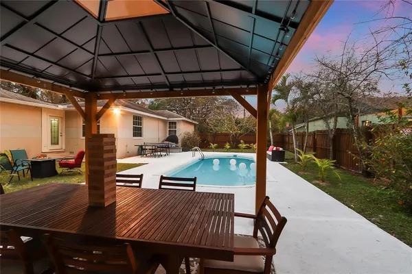 a view of a patio with table and chairs under an umbrella with a small yard