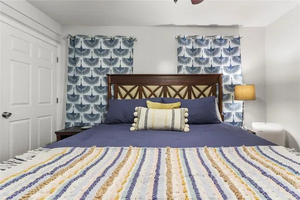 a bedroom with a large bed and a lamp on dresser