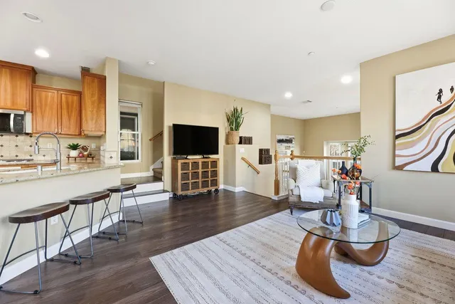 a living room with furniture and kitchen view with wooden floor