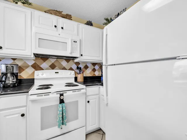 a kitchen with white cabinets and white appliances