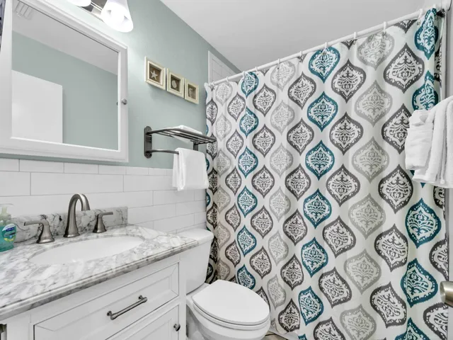 a bathroom with a granite countertop toilet sink mirror and shower