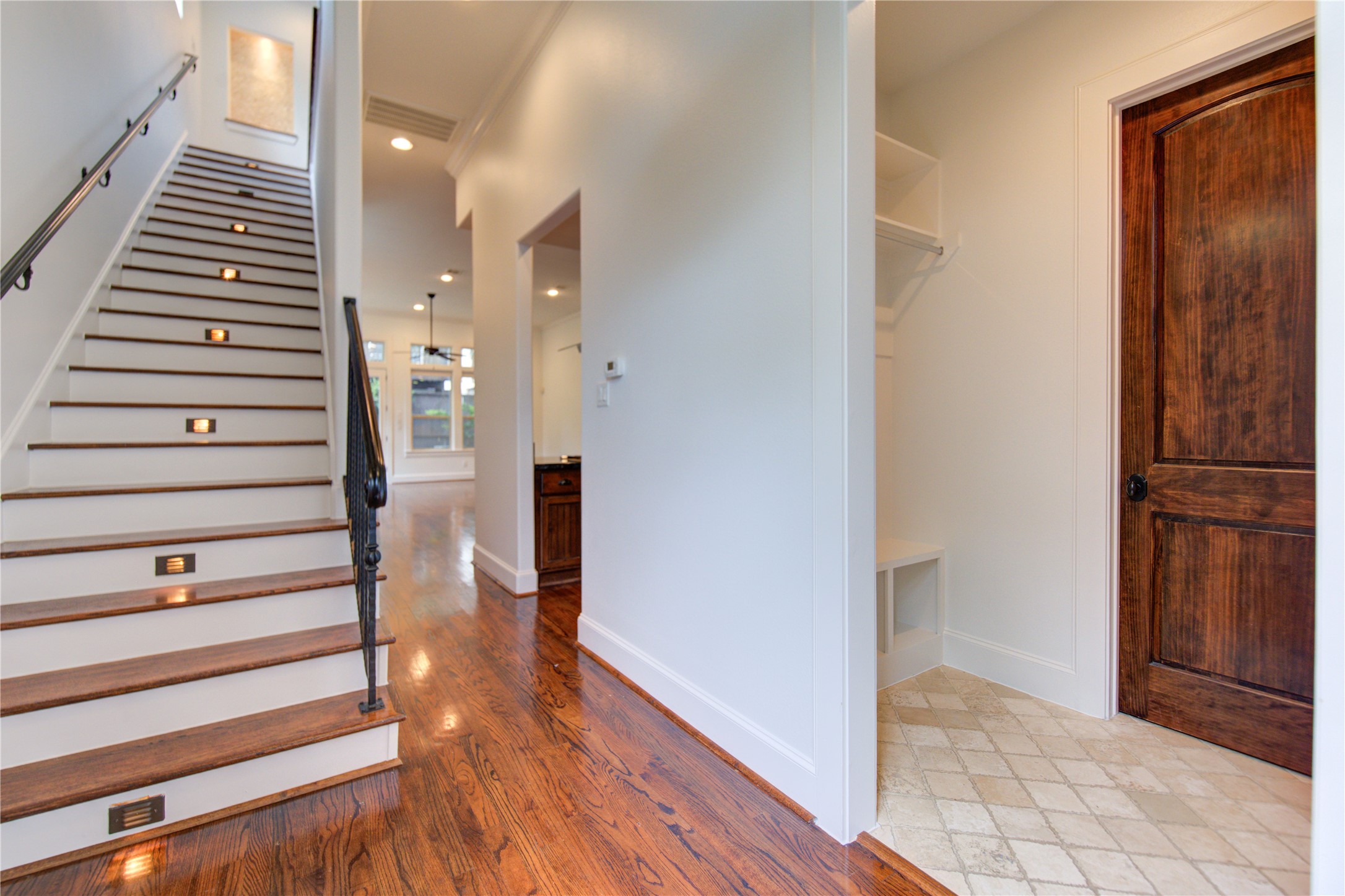 6520 Rodrigo Street Houston, TX 77007 - Photo 4 of 44 Entry hall with hardwood floors, built-in mud area, and staircase with wrought iron railing and step lighting