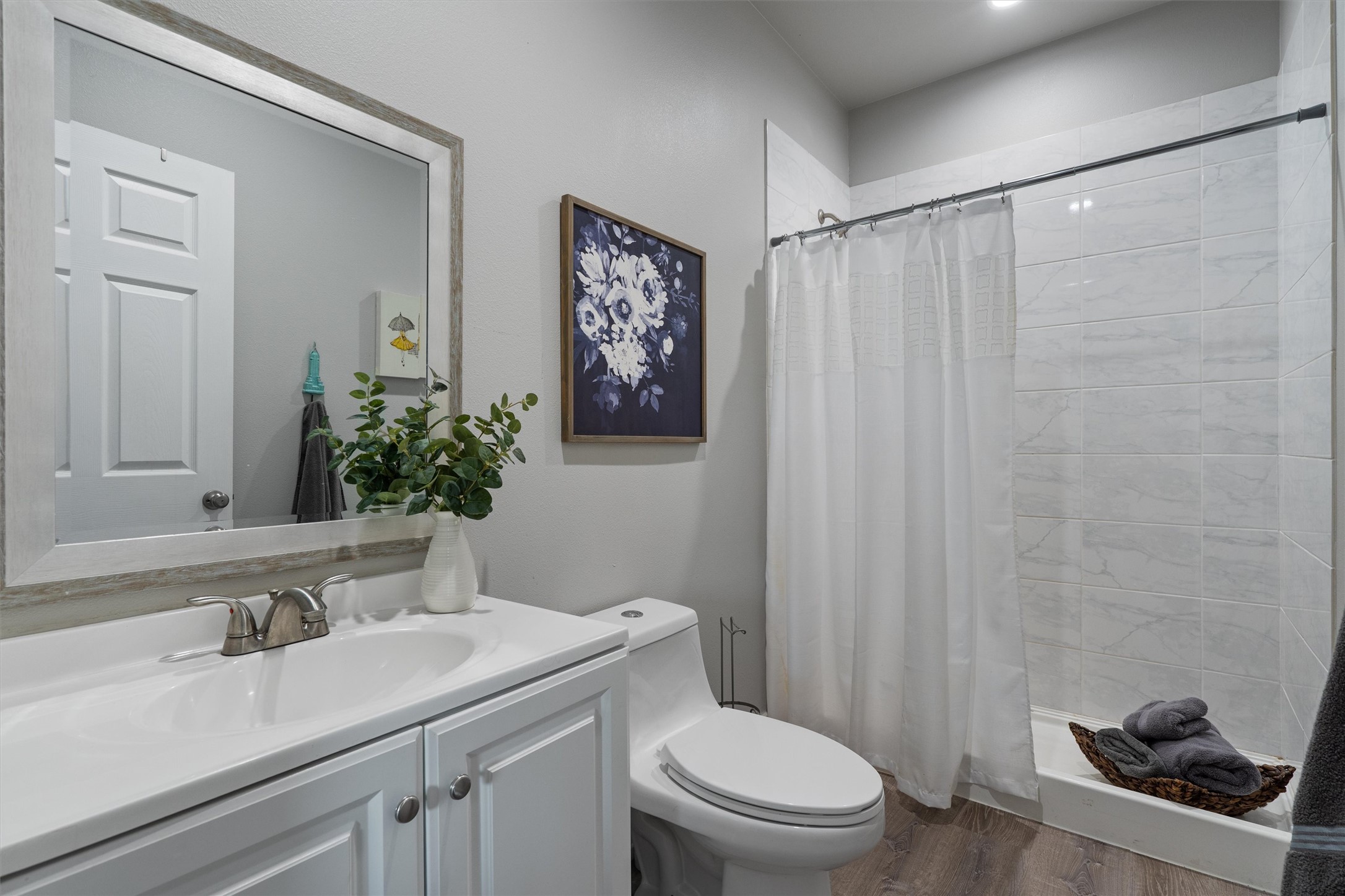 13105 Rooster Springs Road Austin, TX 78737 - Photo 32 of 38 Bathroom with a white vanity featuring a sink and polished chrome faucet, a framed mirror, and a shower with white subway tile
