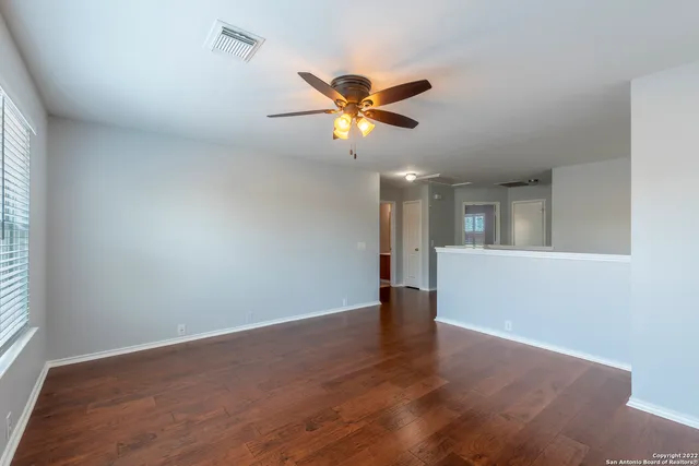 a view of an empty room with window and wooden floor
