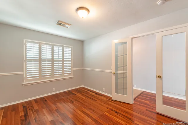 a view of an empty room with wooden floor and a window