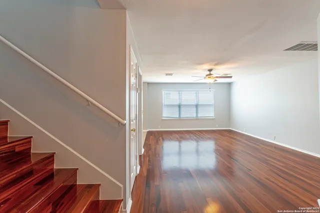 a view of an empty room with wooden floor and stairs