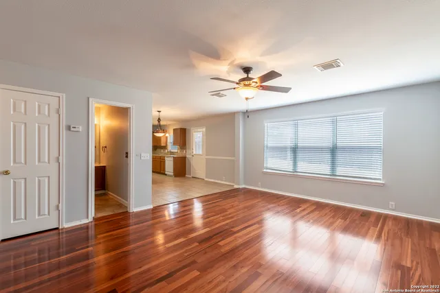 a view of an empty room with window and wooden floor