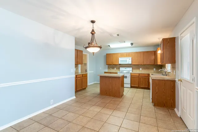 a large kitchen with granite countertop a large counter top a sink stainless steel appliances and cabinets