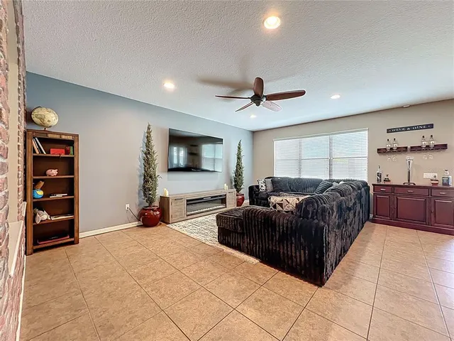 a living room with furniture a ceiling fan and a flat screen tv